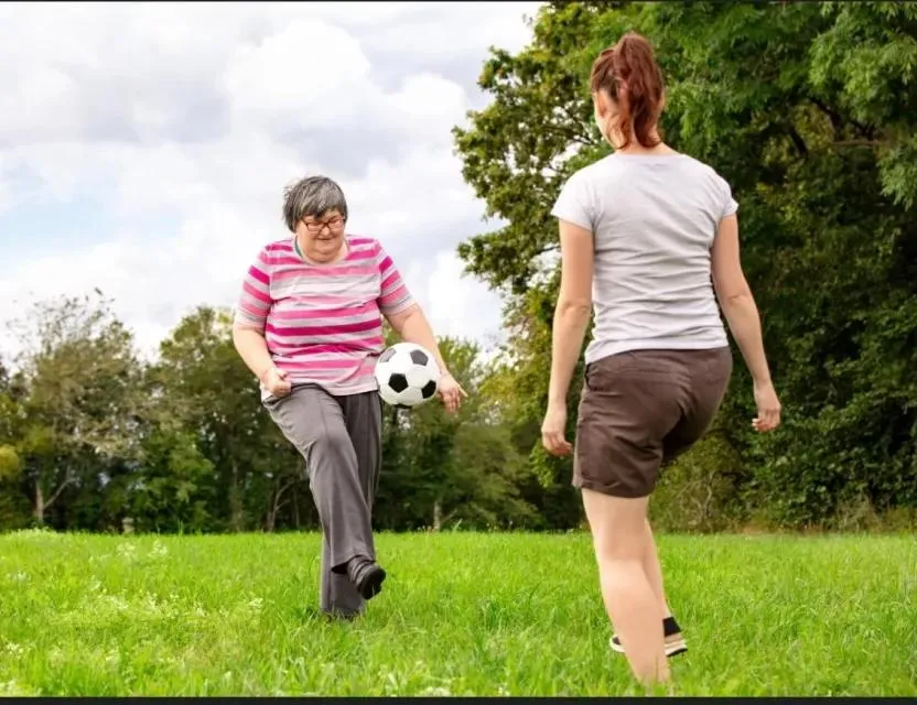 Support worker playing an active game outdoors with a participant