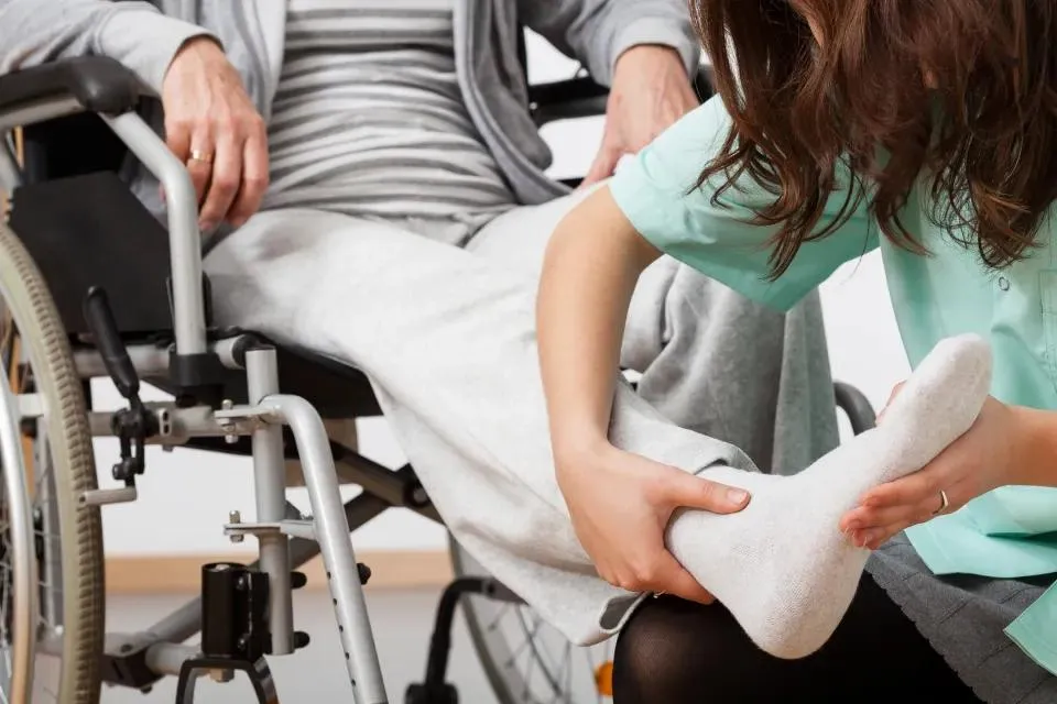 Support worker helping a participant in a wheelchair get dressed