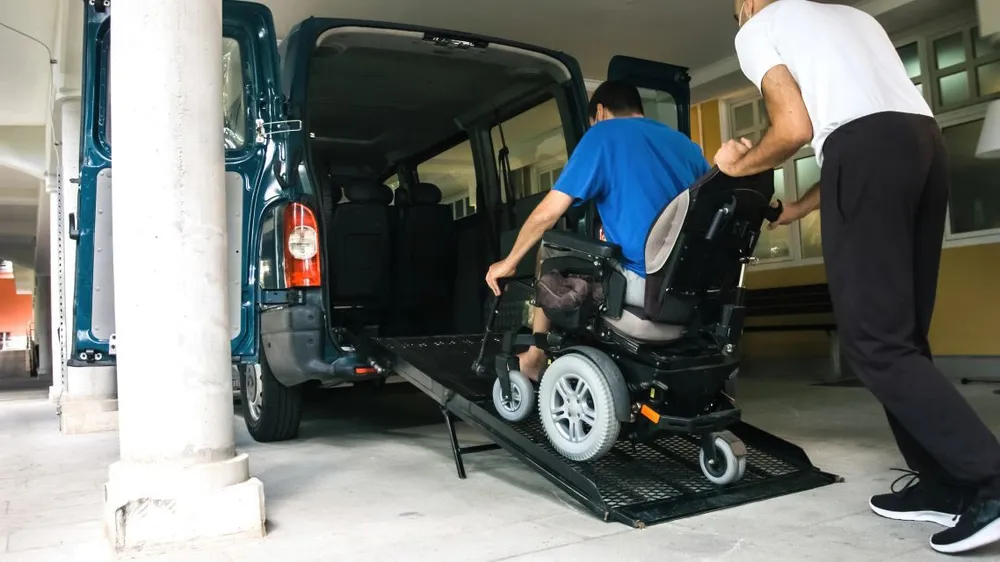 Support worker assisting a participant into a wheelchair-accessible vehicle