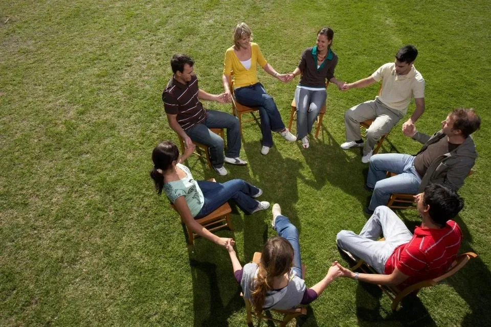 Small group sitting in a circle taking part in a centre-based activity outdoors