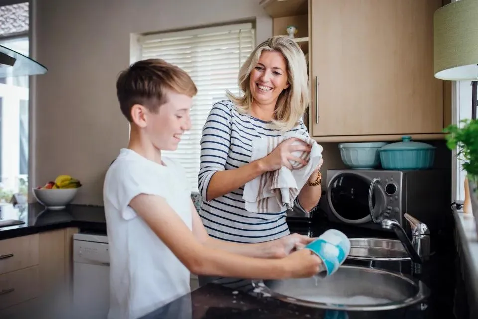 Support worker helping a participant with household chores in the kitchen