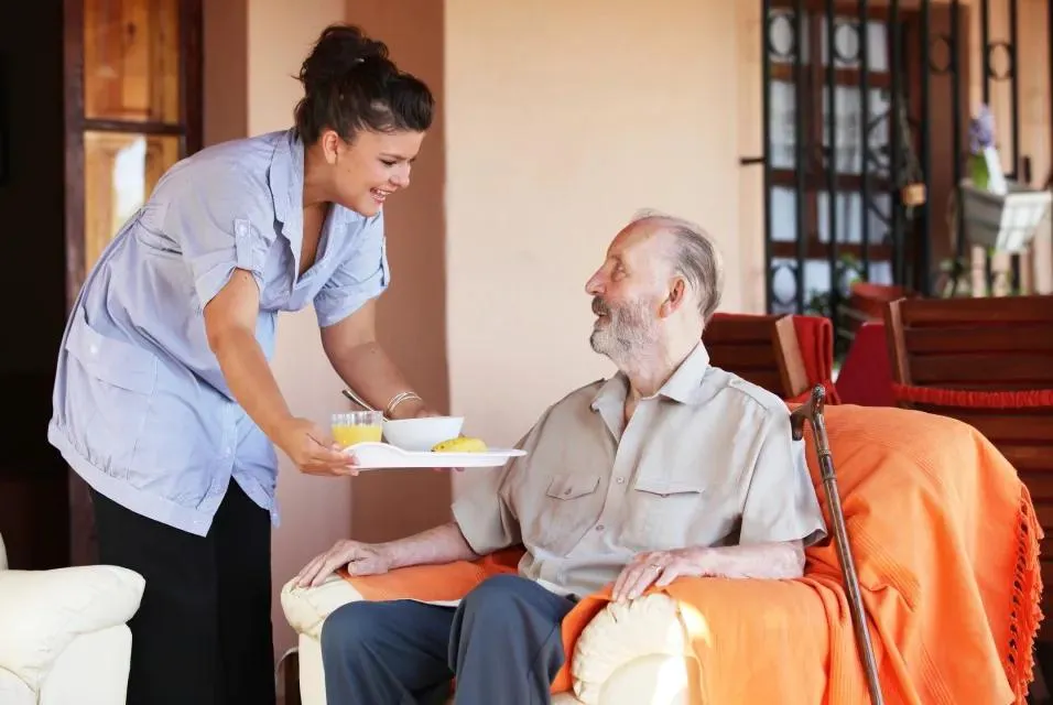 Support worker serving a meal to a participant at home